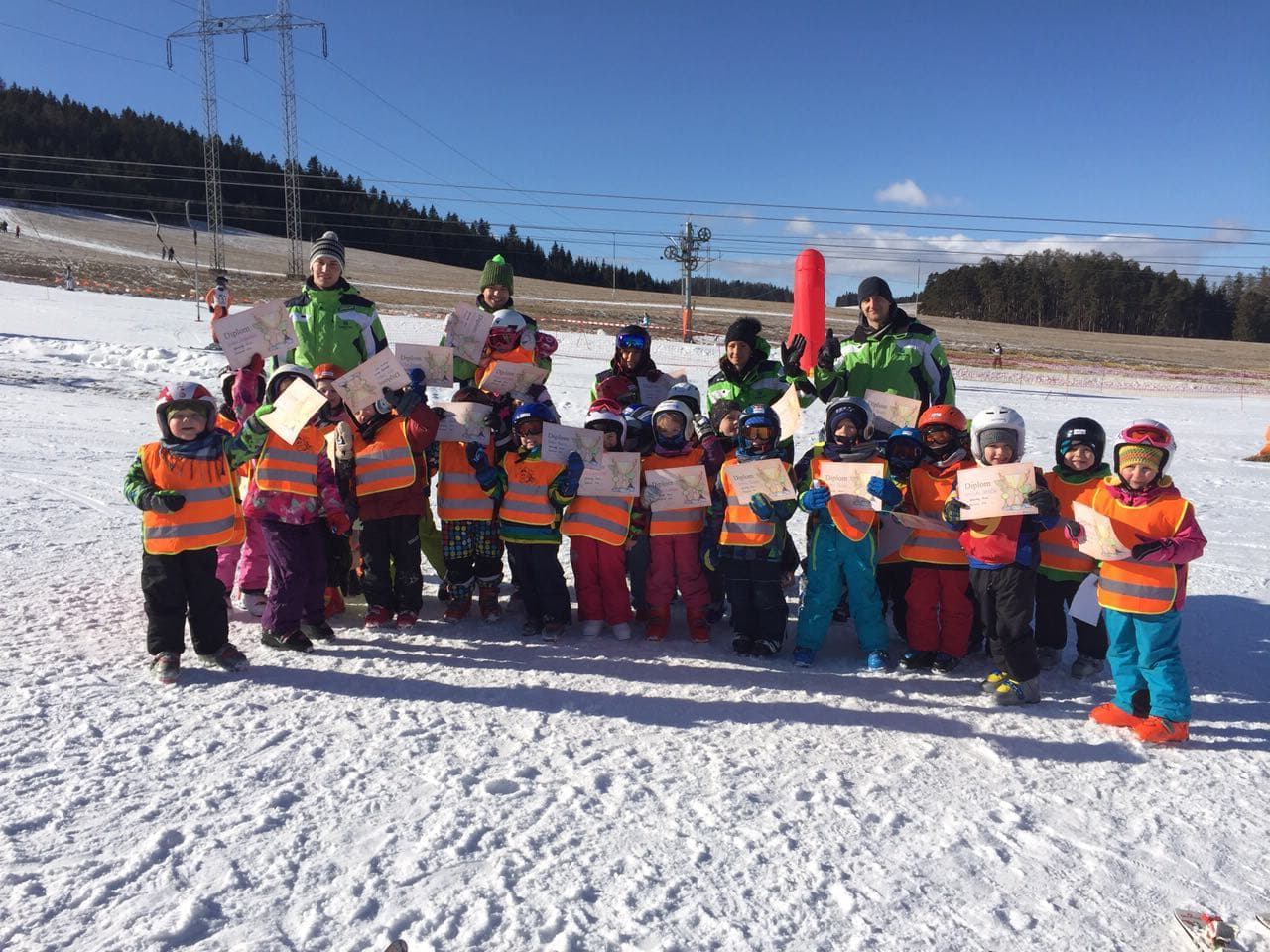 Veľká skupina detí s diplomami a inštruktormi SKI EXPERTS po skončení lyžiarskeho kurzu